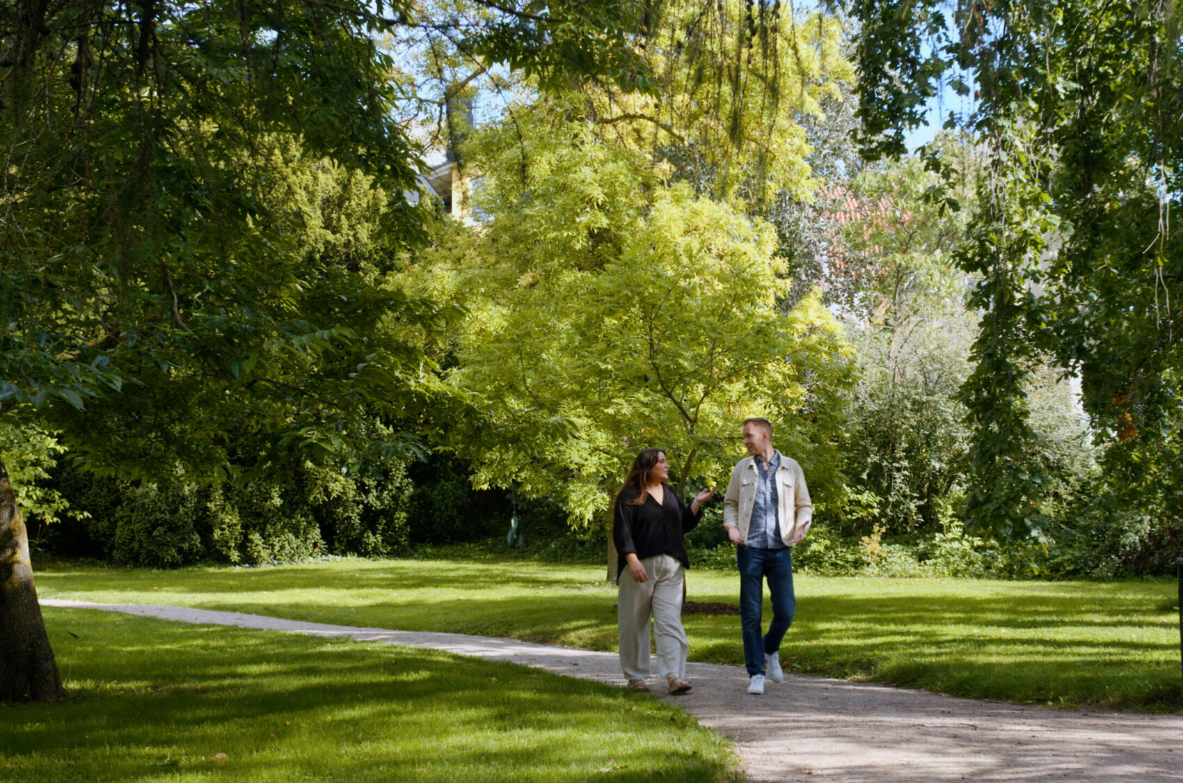 två personer går bland grönskande träd